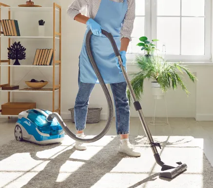 Addetta che aspira il pavimento di un'abitazione con aspirapolvere professionale